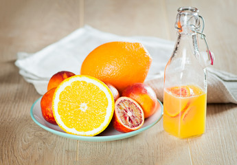 bottle with a fresh juice from the oranges and blood oranges on a wooden surface