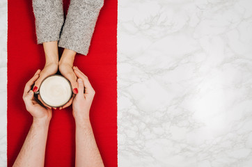 Couple in love holding hands with coffee on white marble table. Photograph taken from above, top view with copy space