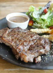 Beef steak, grilled beef steak served with gravy sauce sided vegetables and fries. Soft focus on the steak.