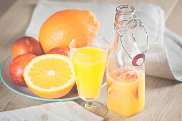 bottle with a fresh juice from the oranges and blood oranges on a wooden surface