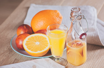 bottle with a fresh juice from the oranges and blood oranges on a wooden surface