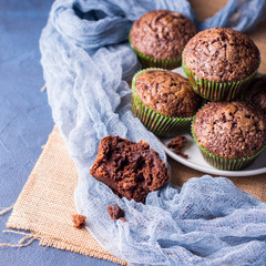 Chocolate banana muffins with sugar topping on dark blue background. Home made single portion snack. Winter baked dessert. Square