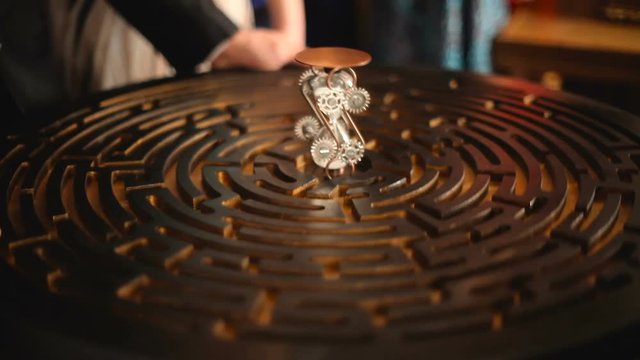 logic game round maze with balls, a man's hand puts the hourglass in the center of the circle