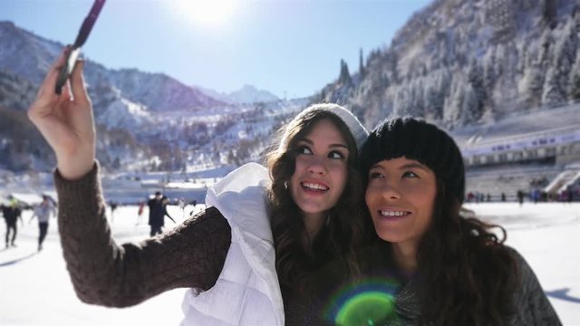 Happy young women making selfie by mobile phone, funny ice skating girls