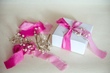 подарок в белой коробке и розовая лента