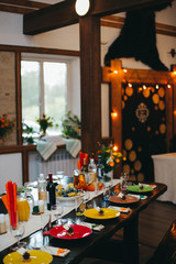 Wedding banquet table with dishes, vine and food. Loft, country and rustic style. Decoration. Arch with bulb garland on background