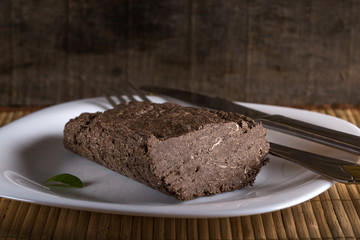 Halvah on white plate with knife and fork on wood