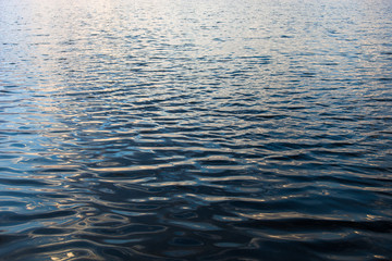 Naklejka premium Water surface with ripples and sunrays reflections