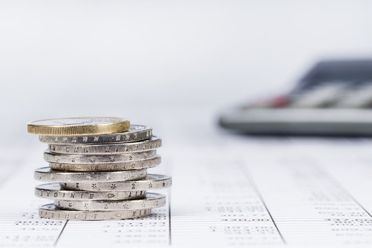 Taschenrechner und ein Stapel Eurom&uuml;nzen auf einer Tabelle, Hintergrund