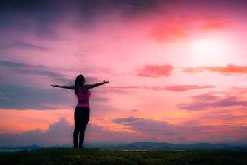 Silhouette healthy woman doing Yoga exercises on the beach in sunset time, Thailand.