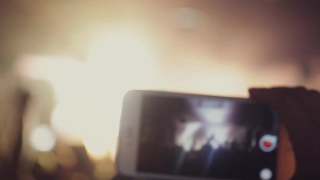 Crowd at concert. Person records rock concert on cellphone in the club in music show on blurred background with beautiful bokeh. 1920x1080