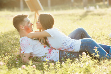 Young beautiful woman laying on her boyfriend wearing colorized t-shirt. Pretty cheerful couple smiling at each other
