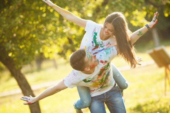 Pretty young couple making a plane or aircraft. Beautiful girl and handsome man having fun outdoors. Looking at each other