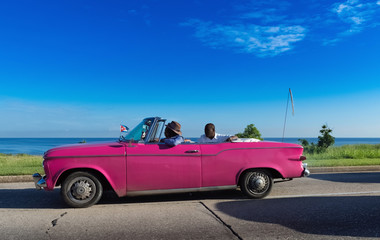 Fototapeta na wymiar Pink farbender Chevrolet Cabriolet Oldtimer auf dem Malecon in Havanna Kuba - Serie Kuba Reportage