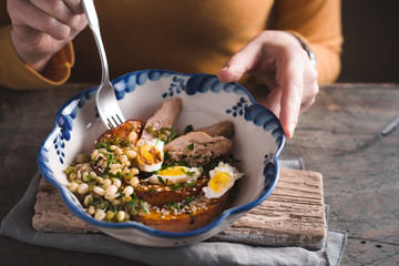 Woman eating a salad with chicken, quail eggs and pumpkin closeup
