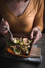 Woman eating a salad with chicken, quail eggs and pumpkin