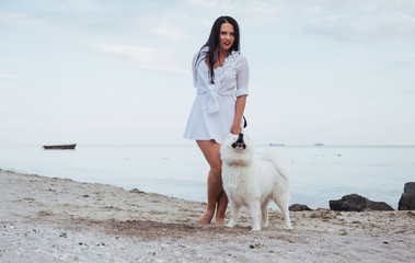 Young beautiful woman walking with her dog on the beach