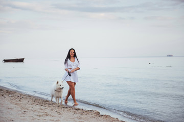 Fototapeta na wymiar Beautiful brunette woman on the beach with a dog walking
