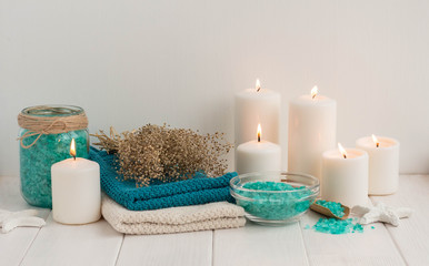 Fototapeta na wymiar Spa composition with candles, sea salt and flowers on white wooden background.