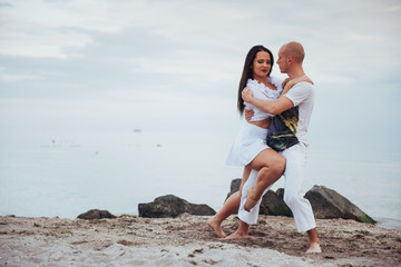 beautiful couple dancing on the beach at the background