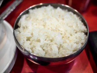 Rice in the metal bowl on the red table Korean style