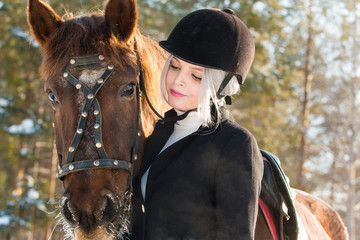 Young beautiful girl jockey and horse in winter forest