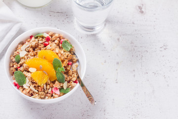 Healthy breakfast - plate of granola with orange slices, mint and seeds, copy space on white table