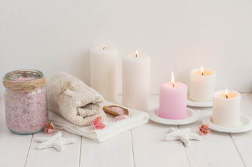 Obraz na płótnie Canvas Spa composition with candles, sea salt and flowers on white wooden background.