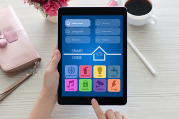 woman at table holding tablet computer with app smart home