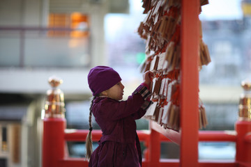 The girl sticks her plate with the wishes of the stand near the Japanese temple