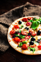 Hot pizza with meat, basil and mozarella cheese on a dark background, top view. Pizza on the rustic wooden  table with copy space.