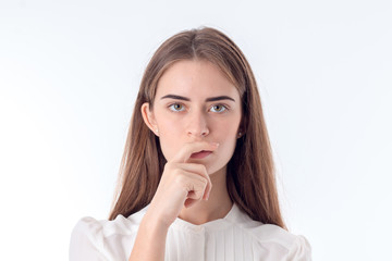 thoughtful young woman looks straight and keeps a hand near the lips isolated on white background