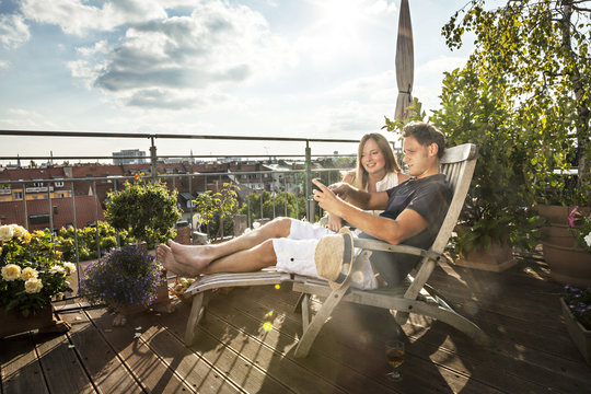 Couple On Balcony Using Mobile Phone, Munich, Bavaria, Germany, Europe
