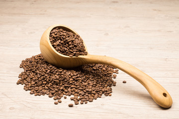 Full of coffee beans wooden ladle lying on coffee beans