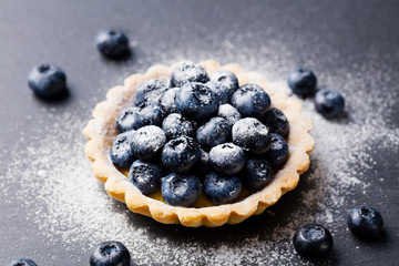 Blueberry tartlet, pie, tart with vanilla custard. Slate stone background. Copy space.