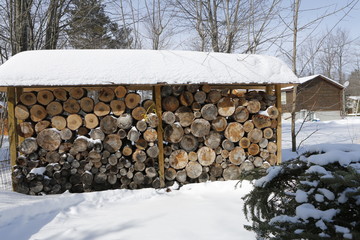 Stack of firewood in bright winter day with a lot of snow around.