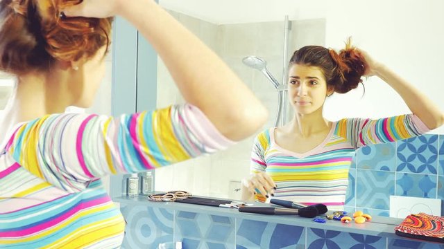 Woman pulling down long hair from bun in the morning