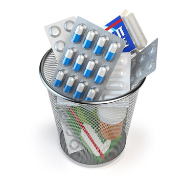 Pills, capsules and medicines thrown in the dustbin isolated on white. End of treatment or healthy lifestyle concept.