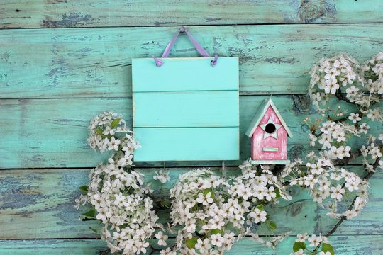 Blank mint green sign by birdhouse and flower border
