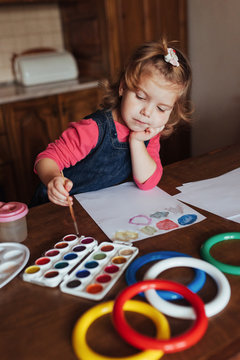 Cute little girl draws a circle of colored paints.