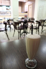 Glass with milkshake on wooden table in cafe