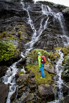 Hiker taking a look at waterfall, Norway, Europe