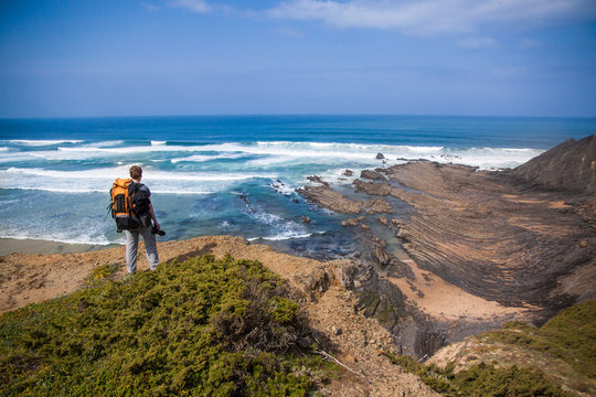 Tourist with backpack on the edge of a beautiful cliff near the ocean Portugal Algarve