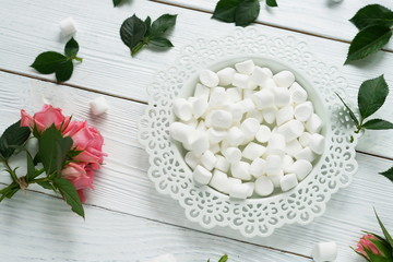 Flat lay still life with roses and marshmallows  on a white wooden background. women's day. 8 march