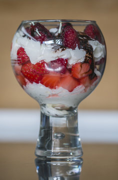 Beautiful glass cup with whipped cream, strawberry, raspberry and chocolate topping.