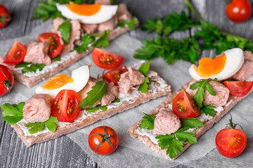 Appetizer of dry loafs with cream cheese, tuna, greens, cherry tomatoes and boiled egg