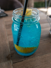 Blue curacao cocktail with lemon on wooden background.