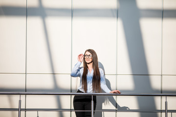 Business woman on balcony in sunny day in modern office building.