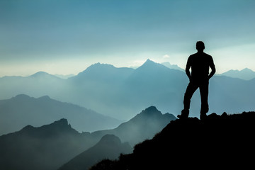 Man watching dreamfully towards spectacular mountain range silhouettes.