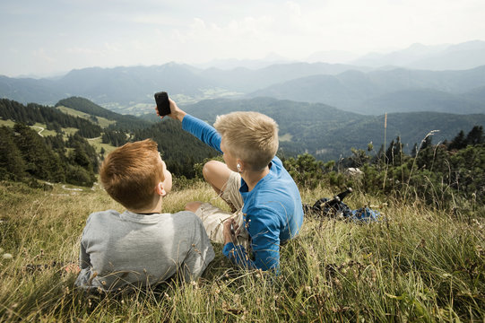 Germany, Bavaria, Two boys in mountains using a smart phone